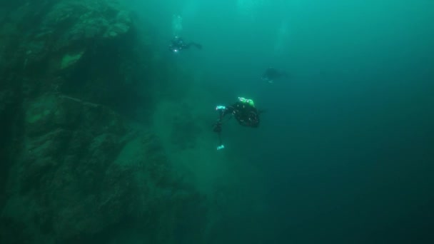 Камери підводного водолаза з групою, що плаває глибоко під водою в озері Байкал.. — стокове відео