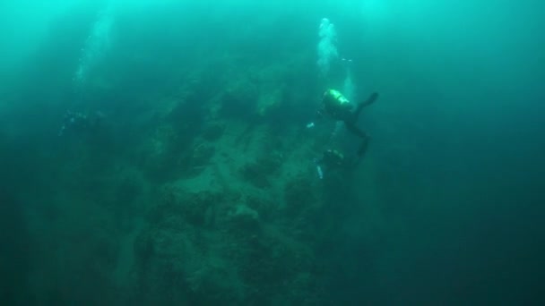 Silhouette di subacquei con macchina fotografica vicino pietre sott'acqua nel lago Baikal . — Video Stock