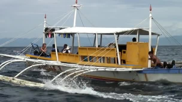 La gente cabalga en barco filipino con alas de bambú en el mar en Filipinas. — Vídeos de Stock