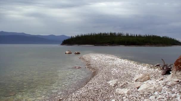 Isla con árboles verdes en el fondo de la costa rocosa del lago Baikal. — Vídeo de stock