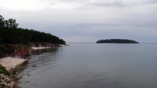 Øya med grønne trær på bakgrunn av Rocky-kysten av Bajkalsjøen. – stockvideo