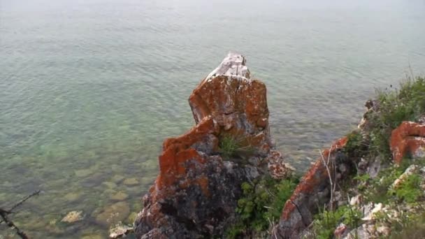 Orange rote Felsen an der Küste des tiefsten Süßwassersees Baikalsee. — Stockvideo