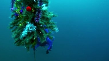 Sualtı Yeni Yıl ve Noel ağacının yanında Noel kostümlü dalgıç.