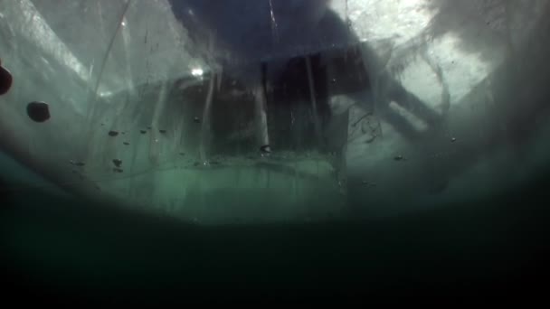 Unterwasser-Videodreh unter Eis von Menschen in der Nähe von Eisloch auf der Oberfläche des Sees. — Stockvideo