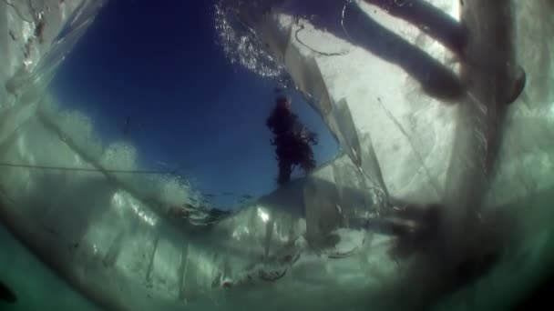 Tournage vidéo sous-marin sous la glace de personnes près d'un trou de glace à la surface du lac . — Video