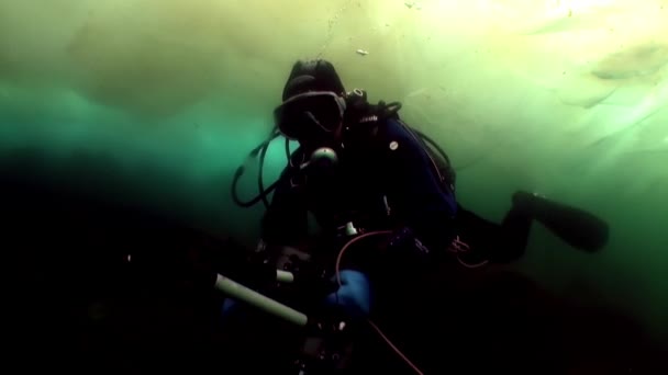 Penyelam juru kamera bawah air di bawah es di dalam air dingin danau Baikal. — Stok Video