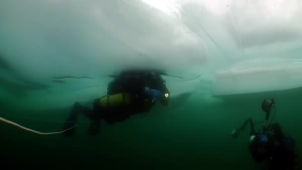 Duiker met onderwater cameraman onder ijs in koud water van het Baikalmeer. — Stockvideo