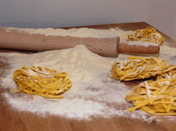 Italské Těstoviny nevařené Tagliatelle na dřevěný stůl s otočným — Stock fotografie