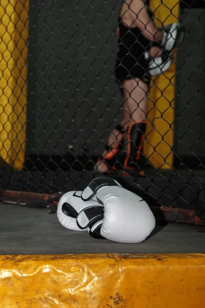 Белые кожаные боксерские перчатки на полу внутри клетки ММА — стоковое фото