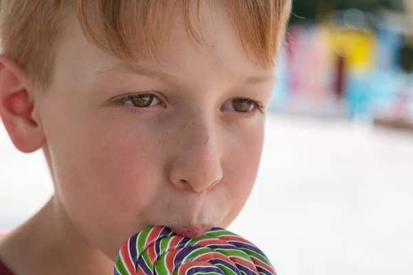 Osiem lat dziecko lizanie kolorowy okrągły lizak — Zdjęcie stockowe