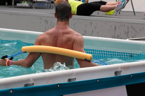 Νέος άνδρας κάνει γυμναστικής αερόμπικ νερού στην πισίνα στο L — Φωτογραφία Αρχείου