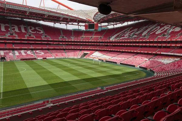 Pohled na Da Luz stadionu: červená prázdná sedadla a zelené fotbalové hřiště — Stock fotografie