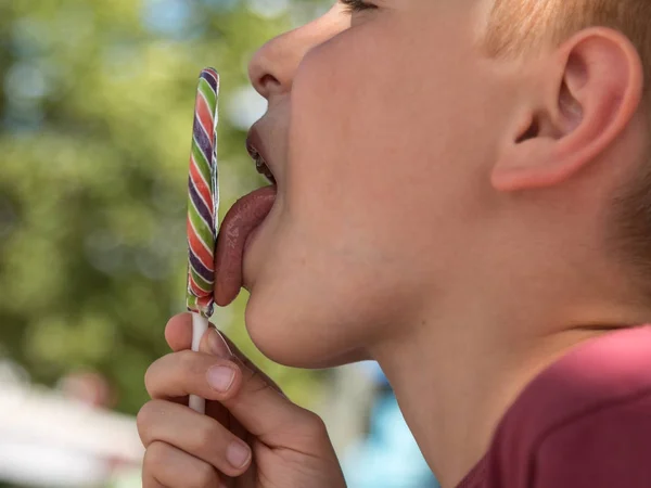 Achtjähriges Kind leckt bunten runden Lutscher — Stockfoto