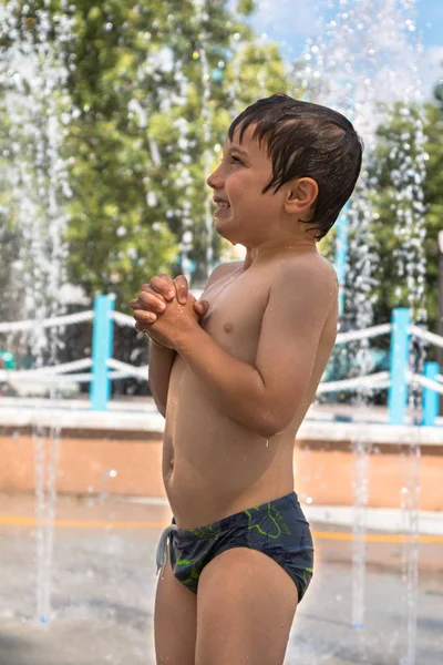 Fröhlicher Junge spielt mit Wasser in Brunnen auf öffentlichem Grund in Summe — Stockfoto