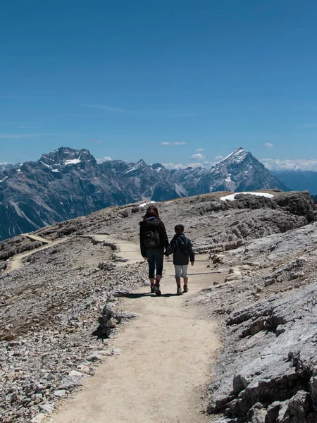 Mor og sønn, vandrende i steinstien blant ufruktbare fjell i I – stockfoto