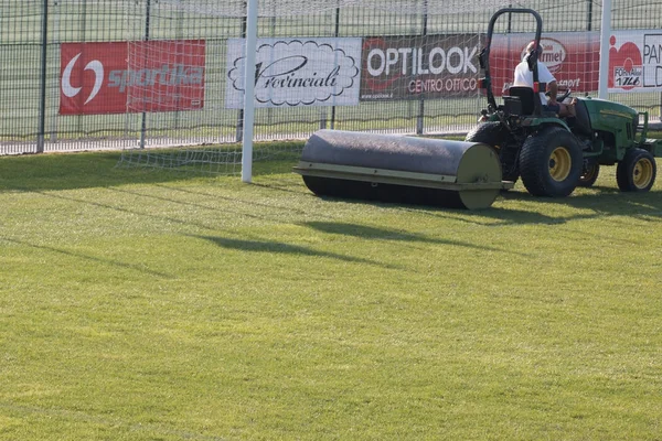 Worker Drives Lawn Equipment in Soccer Pitch before Match