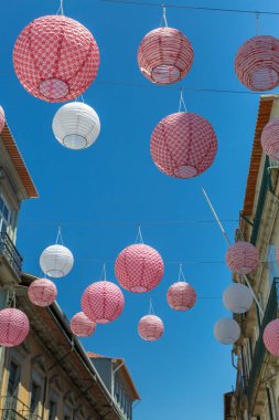 Porto sokakta ev arasında pembe küresel kağıt fenerler astı