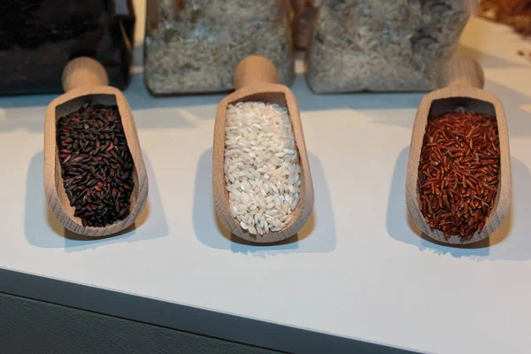 Czerwony, brązowy i biały niegotowane ryżu w duże drewniane łyżki — Zdjęcie stockowe