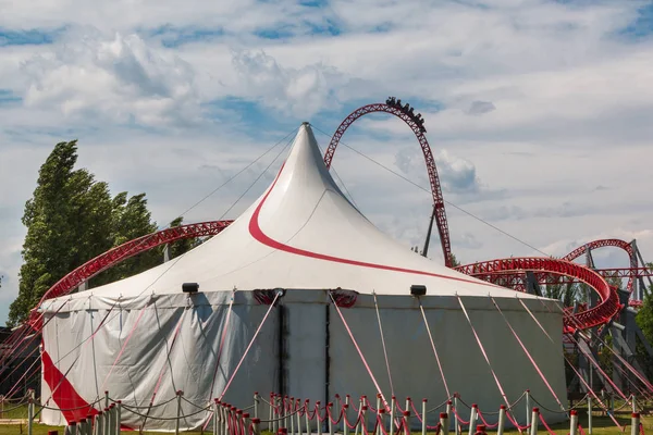 Cirkustält och röda berg-och dalbana inuti offentliga nöjespark — Stockfoto