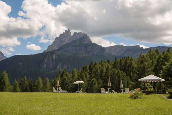 Reposeras de sol blancas y sombrillas en Green Meadow en el paisaje italiano de los Alpes Dolomitas — Foto de stock gratis