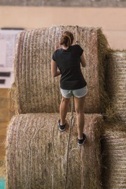 Kapalı saman balya engel: yarışma çalıştıran insanlar balya ipi ile tırmanmaya.