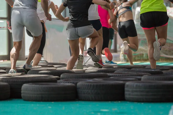 Emberek fut át a gumiabroncs Fitness akadály edzés közben — Stock Fotó