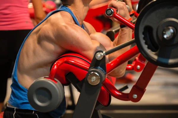 Baiat muscular: antrenament la sala de sport cu echipament rosu pentru bicepsi — Fotografie, imagine de stoc