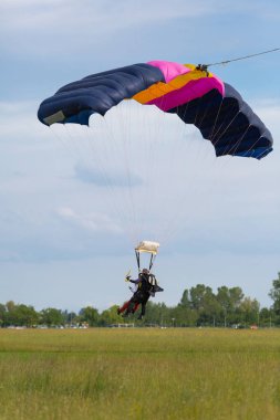 Reggio Emilia, İtalya - Mayıs 2017: Paraşütçüler: eğitmen ve acemi mavi paraşüt karşı açık mavi gökyüzü