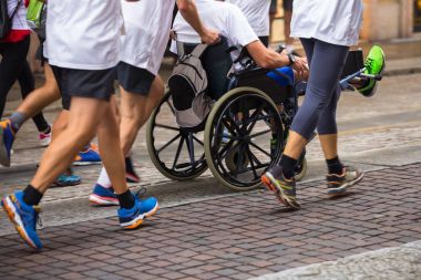 Maraton koşucular tarafından yardımcı sırasında spor tekerlekli sandalyeli Engelli sporcu