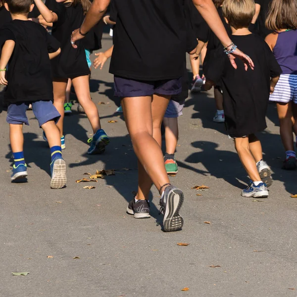 Bambini con camicia nera che corrono nel parco con giovane insegnante — Foto Stock