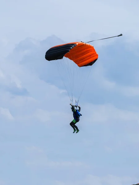 Parachutiste avec parachute orange contre ciel bleu clair — Photo