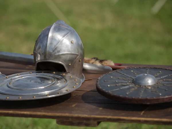 Helmets, Shields and Medieval Metallic Armors and Weapons, Outdoors on Wooden Table — Stock Photo, Image