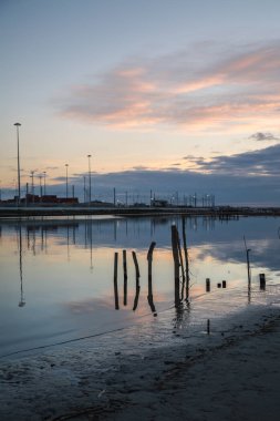 Ahşap direklerin ve gün batımında kuşlar: su yansıma