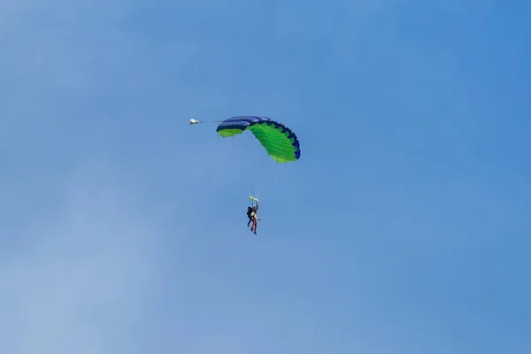 落下傘兵: インストラクターと緑の初心者は、澄んだ青い空を背景パラシュートします。 — ストック写真