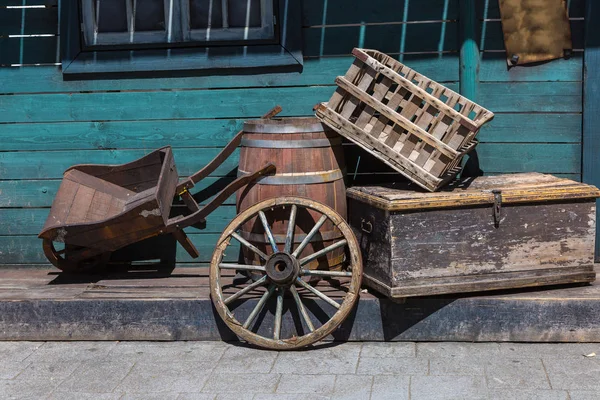 Roda de carruagem ocidental, carrinho de mão de madeira, barril e caixas na rua — Fotografia de Stock