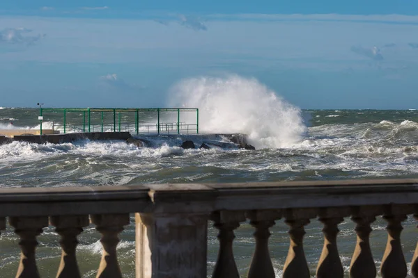 Les vagues de la mer se brisent contre la promenade au bord de la mer par temps venteux : temps orageux — Photo