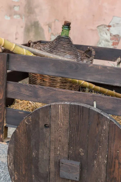 Jarra de mimbre de vino en carro de madera antiguo — Foto de Stock