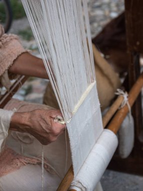 Yaşlı kadının eski ahşap tezgah üzerinde dokuma beyaz desen eller
