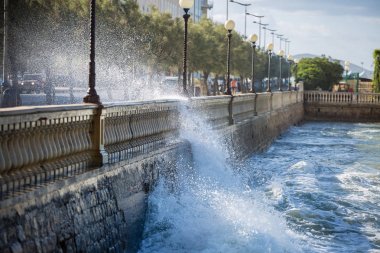 Sea Waves Breaking against the Parapet of a Road in Windy Day: Stormy Weather clipart