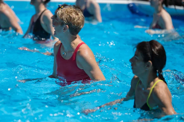 Nő csinálás víz aerobik Outdoor egy úszómedence — Stock Fotó
