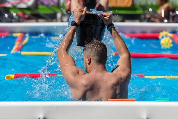 Хлопчик робить водні вправи у відкритому басейні Спорожнивши відро води на голові — стокове фото