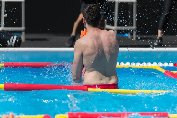 Chłopiec robi aerobik wodny z hantlami pływającymi na zewnątrz basenu — Zdjęcie stockowe
