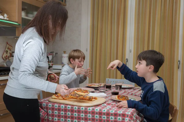 Familia de cuatro personas comiendo pizza en la mesa de la cocina en casa — Foto de Stock