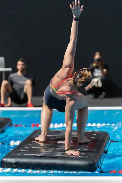 Flicka gör övningar på flytande träningsmatta i en utomhuspool — Stockfoto