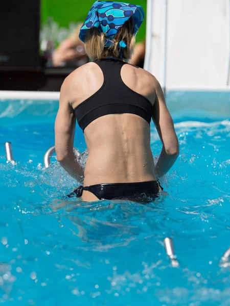 Mädchen macht Wassergymnastik mit Fahrrad im Freien in einem Schwimmbad — Stockfoto
