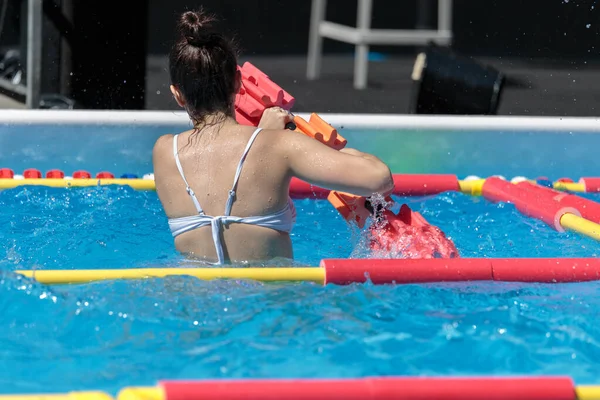 Mädchen macht Wassergymnastik mit schwimmenden Poolhanteln im Freien in einem Schwimmbad — Stockfoto