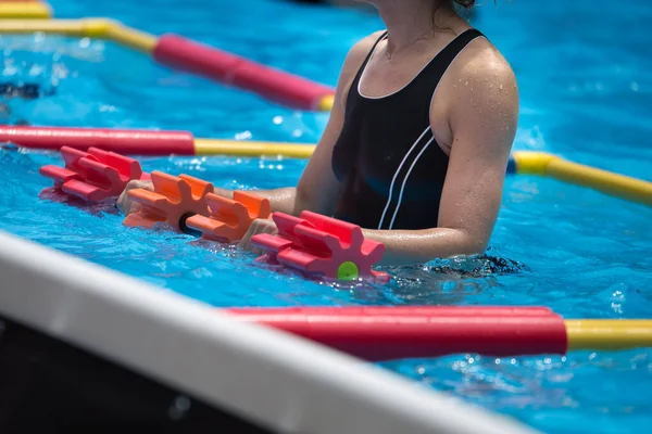 Dziewczyny wykonujące aerobik wodny z hantlami pływającymi na zewnątrz basenu — Zdjęcie stockowe