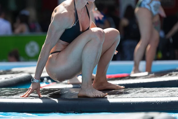 Menina fazendo exercícios no tapete de fitness flutuante em uma piscina ao ar livre — Fotografia de Stock