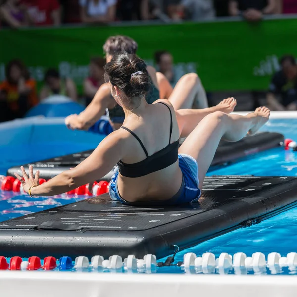 Ρίμινι, Ιταλία - Μάιος 2019: Κορίτσι που κάνει ασκήσεις στο Floating Fitness Mat σε μια εξωτερική πισίνα — Φωτογραφία Αρχείου