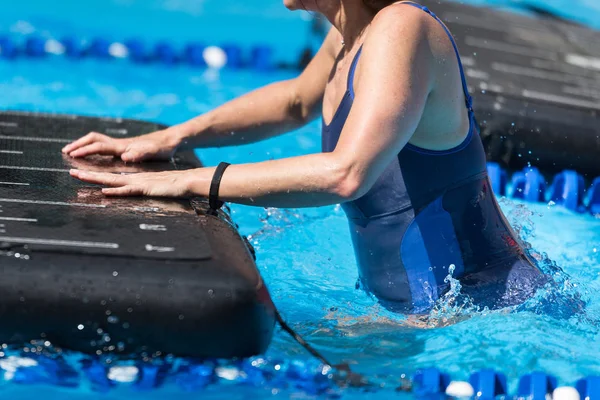 Flicka gör övningar på flytande träningsmatta i en utomhuspool — Stockfoto